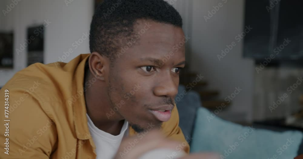 Portrait of overjoyed African American guy student watching baseball game on TV cheering supporting having fun at home. Sports and youth concept. Portrait of overjoyed African American guy student watching baseball game on TV cheering supporting having fun at home. Sports and youth concept.
