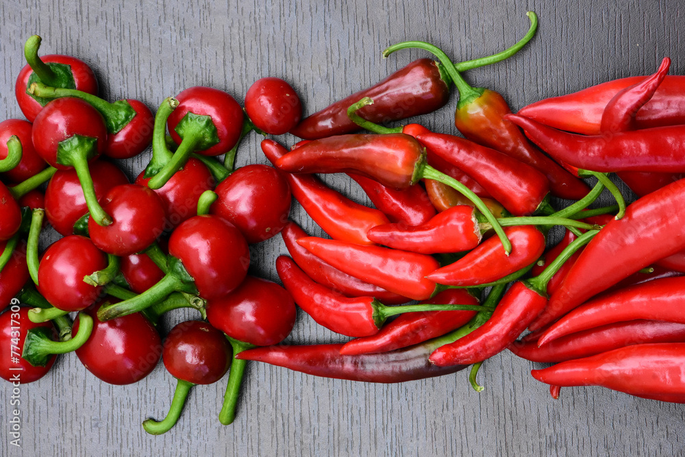 Pile of hot peppers border with space for text. Different red hot chili peppers. Long, cherry and small red peppers