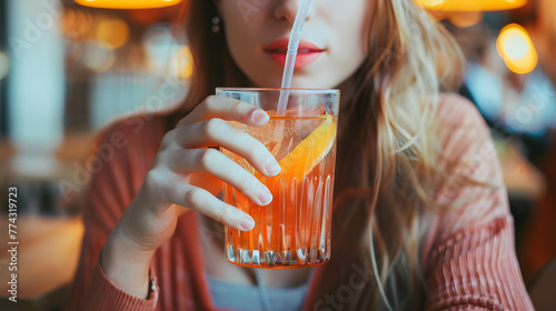 Playful Moment: Woman Enjoying a Refreshing Drink with a Straw, Capturing the Essence of Relaxation and Carefree Pleasure photo
