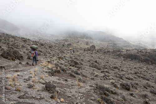 A porter carries the goods to the next camp site along the Lemosho route on Mount kilimanjaro. photo