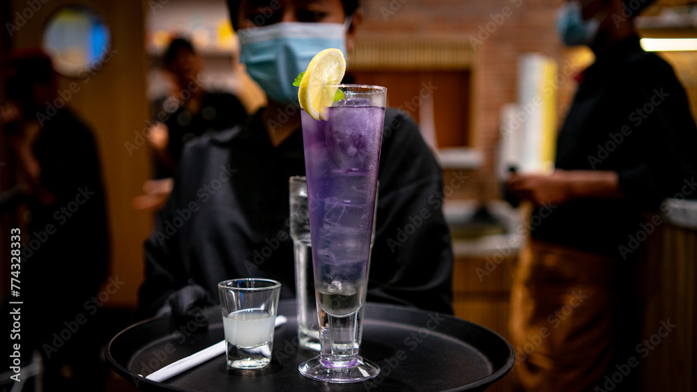 The female waitress brought a Fresh Blue Mojito on a tray