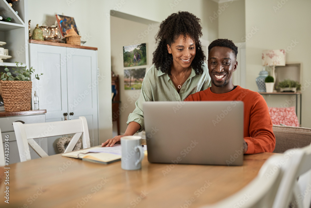 Smiling multiracial couple taking care of their online banking at home Smiling multiracial couple taking care of their online banking at home