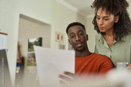 Young multiracial couple doing online banking together at home