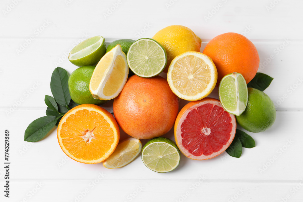 Different fresh citrus fruits and leaves on white wooden table, flat lay Different fresh citrus fruits and leaves on white wooden table, flat lay