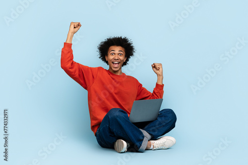 Excited man with laptop celebrating photo