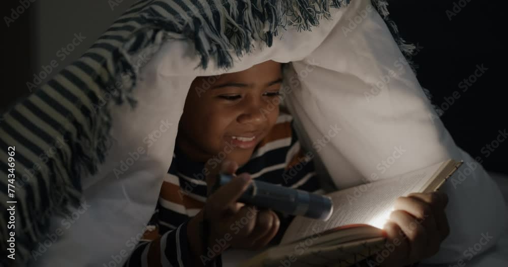 Adorable child reading book holding flashlight lying in bed under blanket enjoying night at home. Childhood and literature concept. Adorable child reading book holding flashlight lying in bed under blanket enjoying night at home. Childhood and literature concept.
