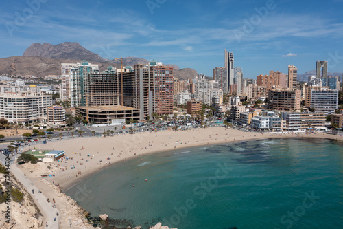 Aerial drone photo of the town of Benidorm in Spain in the summer time showing the beach known locally as Playa de Finestrat and hotels and apartments around the small beach © Duncan