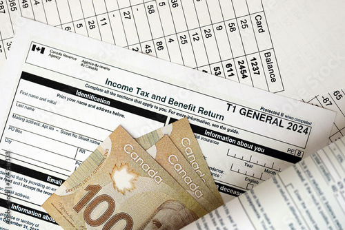 Canadian T1 General tax form Income tax and benefit return lies on table with canadian money bills close up. Taxation and annual accountant paperwork in Canada photo