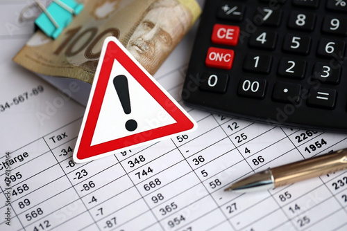 Attention sign and calculation results in schedules lies on table with canadian money bills, calculator and pen close up. Taxation and annual accountant paperwork in Canada photo