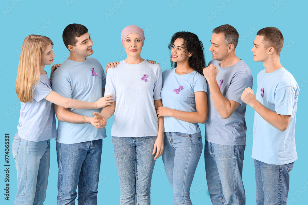 Obraz premium Mature woman after chemotherapy and people with lavender awareness ribbons on blue background. World Cancer Day
