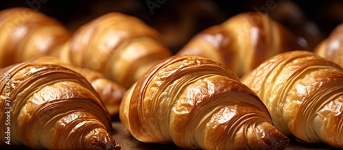 Display of assorted freshly baked croissants neatly arranged in rows on a wooden table in a cozy bakery setting