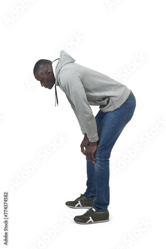 Side view portrait of a crouching man looking down on white background.