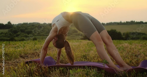 Young woman doing yoga in nature, wearing a white top and olive-colored shorts.