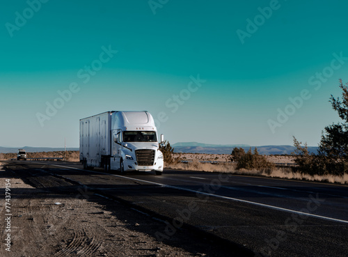 Winter Arizona road trip: A white truck travels through the stunning landscape of the American Southwest. Featuring rugged mountains and a blue sky, it's ideal for adventure and travel themes.