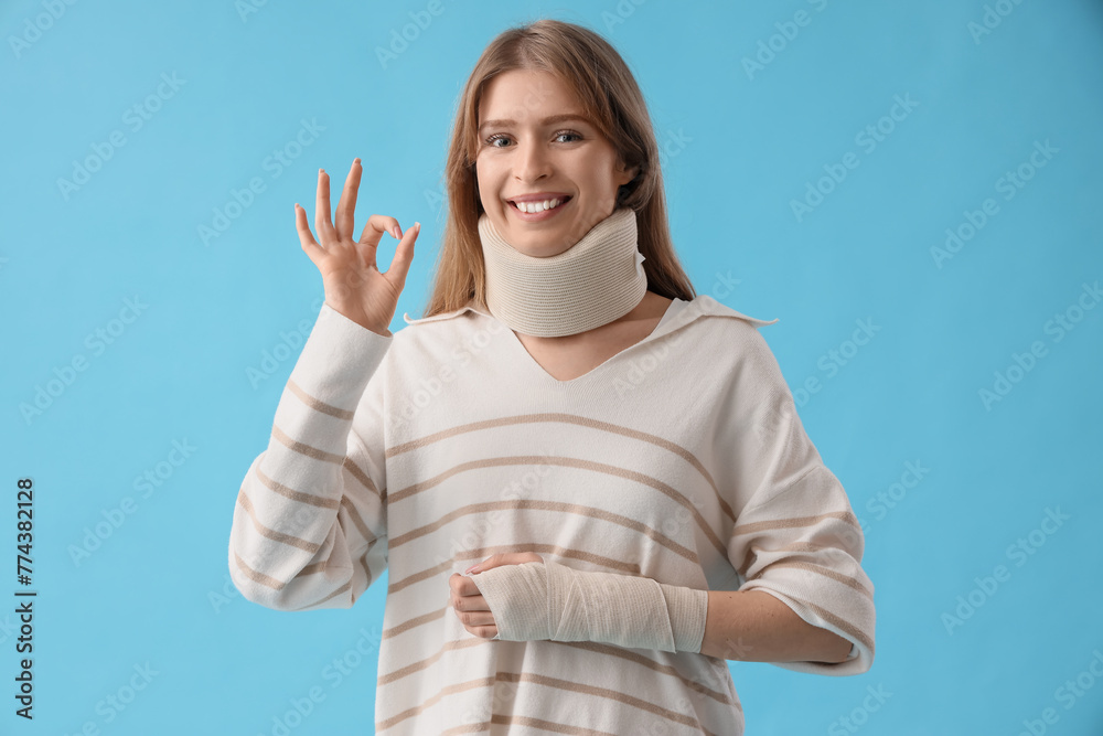 Injured young woman after accident showing OK on blue background Injured young woman after accident showing OK on blue background