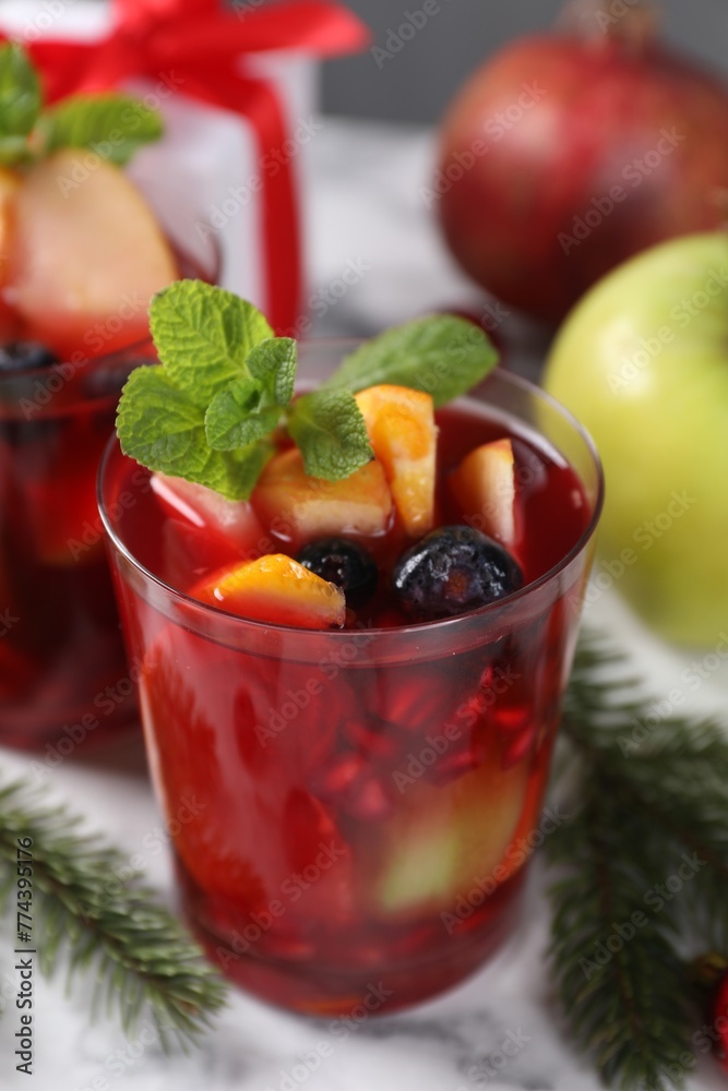 Aromatic Sangria drink in glasses, ingredients and Christmas decor on white marble table Aromatic Sangria drink in glasses, ingredients and Christmas decor on white marble table