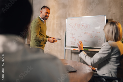 Manager on seminar at boardroom asking questions his interracial colleagues
