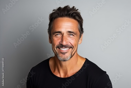 Handsome middle aged man smiling at the camera while standing against a grey background