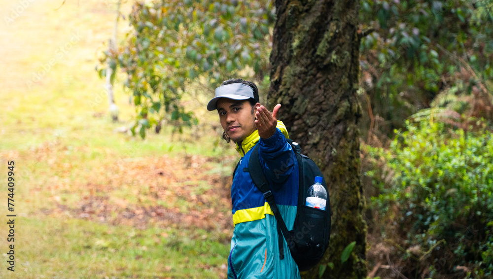 hiker with cap and colorful waterproof jacket calling to his partners