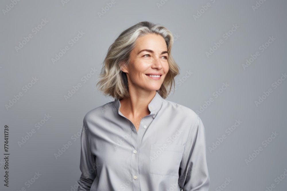 Portrait of smiling mature businesswoman in white shirt, over grey background. Portrait of smiling mature businesswoman in white shirt, over grey background.
