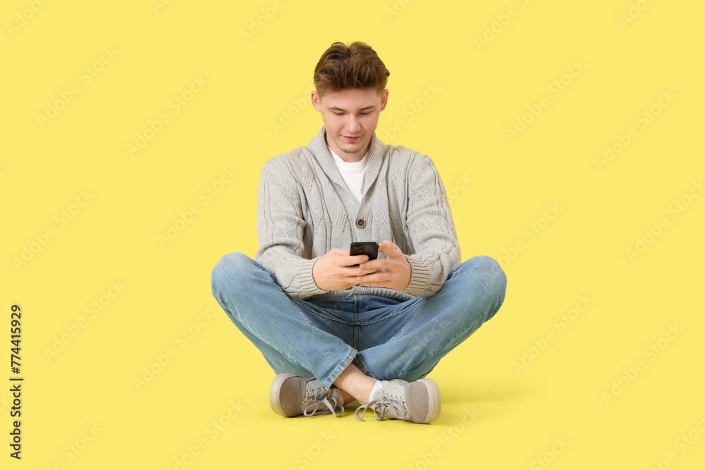 Young man using mobile phone on yellow background Young man using mobile phone on yellow background