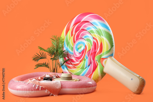 Swimming mattress in shape of candy and heart with photo camera on orange background