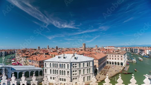 Top panoramic view on central busy canal in Venice timelapse, on both sides masterpieces of Venetian architecture, sailing on gondolas and boats. Blue cloudy sky at summer day over red roofs photo