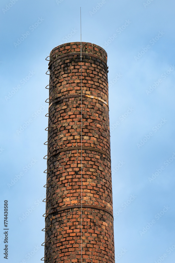 historic factory chimney made of masonry brick with crampons and modern lightning conductor