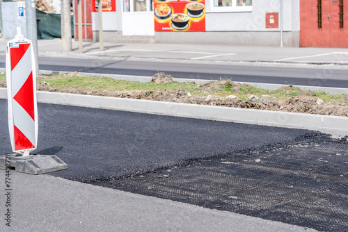 Unfinished asphalt road, metal reinforcing mesh, laying new asphalt, pavement under construction. old and new asphalt