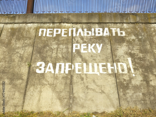 it is forbidden to cross the river - an inscription on the wall in Russian letters about the prohibition to cross the river. danger in the water or unequipped place for swimming photo