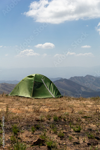 Green camping tent on top of mountain in the middle of day. Time spending in the outdoors. Hiking concept.