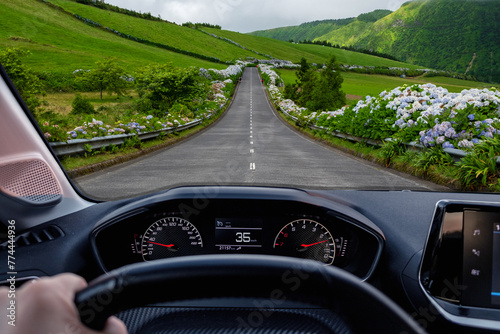 Driver view to the road with beautiful green landscape view from inside a car of driver POV. São Miguel island, Azores, Portugal, Europe.