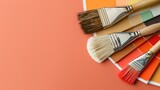 Paintbrushes rest on a coral background with palette of color swatches