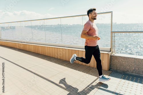 A spirited man jogs along a sunlit promenade by the sea, the joy of exercise evident in his stride and demeanor.