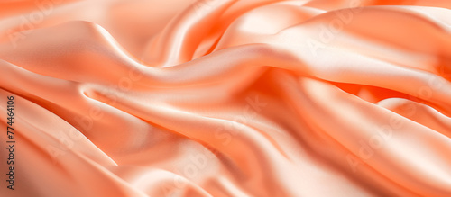 Beautiful background luxury cloth with drapery and wavy folds of peach fuzz color creased smooth silk satin material texture. Abstract monochrome luxurious fabric background