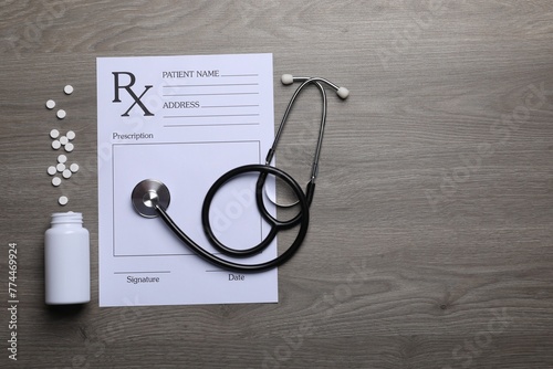 Medical prescription form, stethoscope and pills on wooden table, flat lay. Space for text