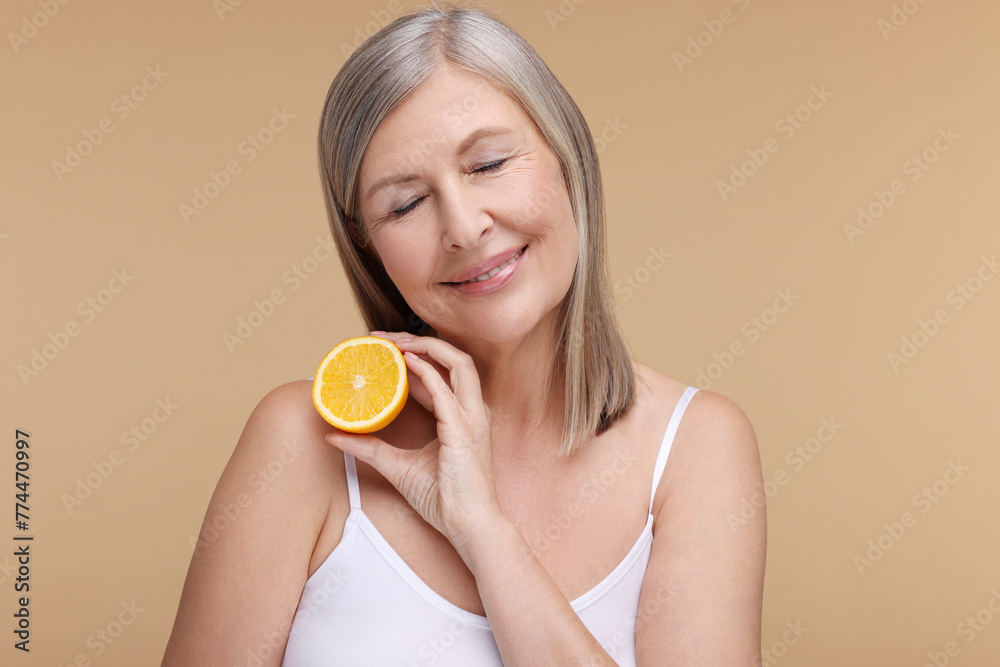 Beautiful woman with half of orange rich in vitamin C on beige background Beautiful woman with half of orange rich in vitamin C on beige background
