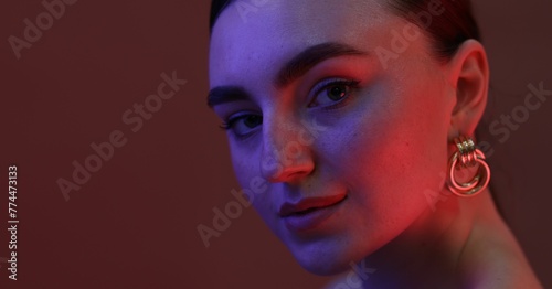 Portrait of beautiful young woman on color background in neon lights, closeup. Space for text