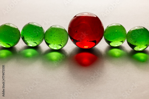 A row of green marbles with one red marble.