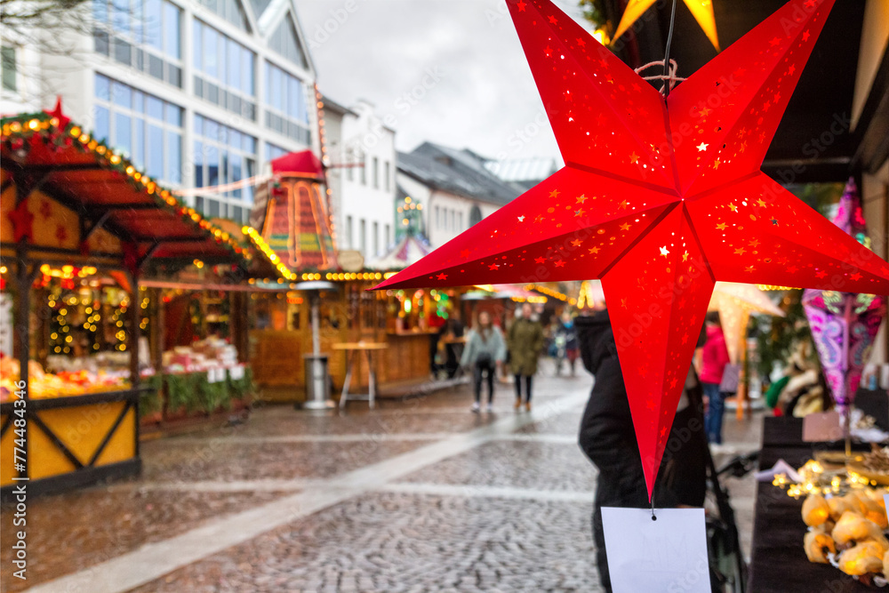 Holiday cityscape - view of star in the form of decoration on background of the Christmas Market (Weihnachtsmarkt) in the city of Bonn, Germany