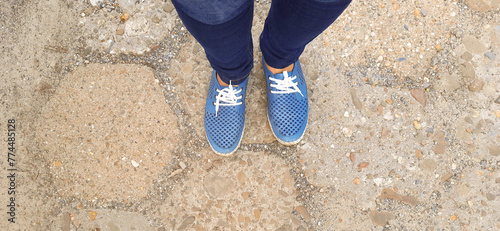 Banner with Legs in blue moccasins and jeans. Selfie from personal perspective. Feet in sneakers on old stone road. Overhead view. Theme of active lifestyle, travel, walking. Header for blog, website.