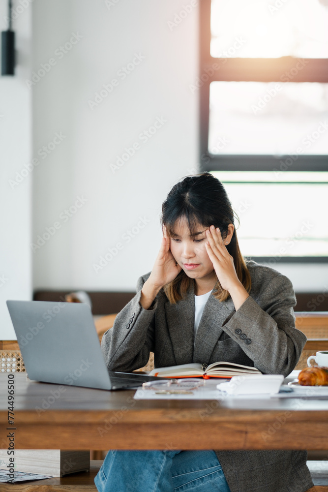 Exhausted young professional feeling stressed while working on laptop in a cafe, reflecting common work challenges. Exhausted young professional feeling stressed while working on laptop in a cafe, reflecting common work challenges.