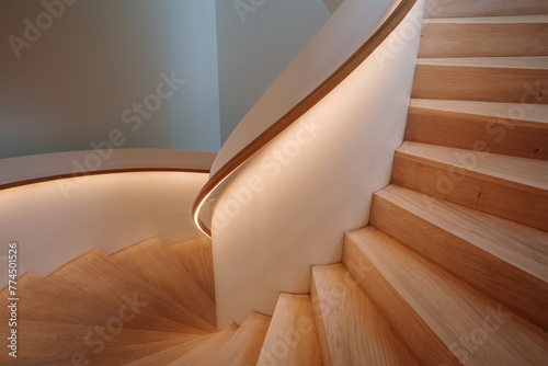 Interior staircase featuring a smooth curve, with warm light emanating from the built-in illumination along the handrail. 