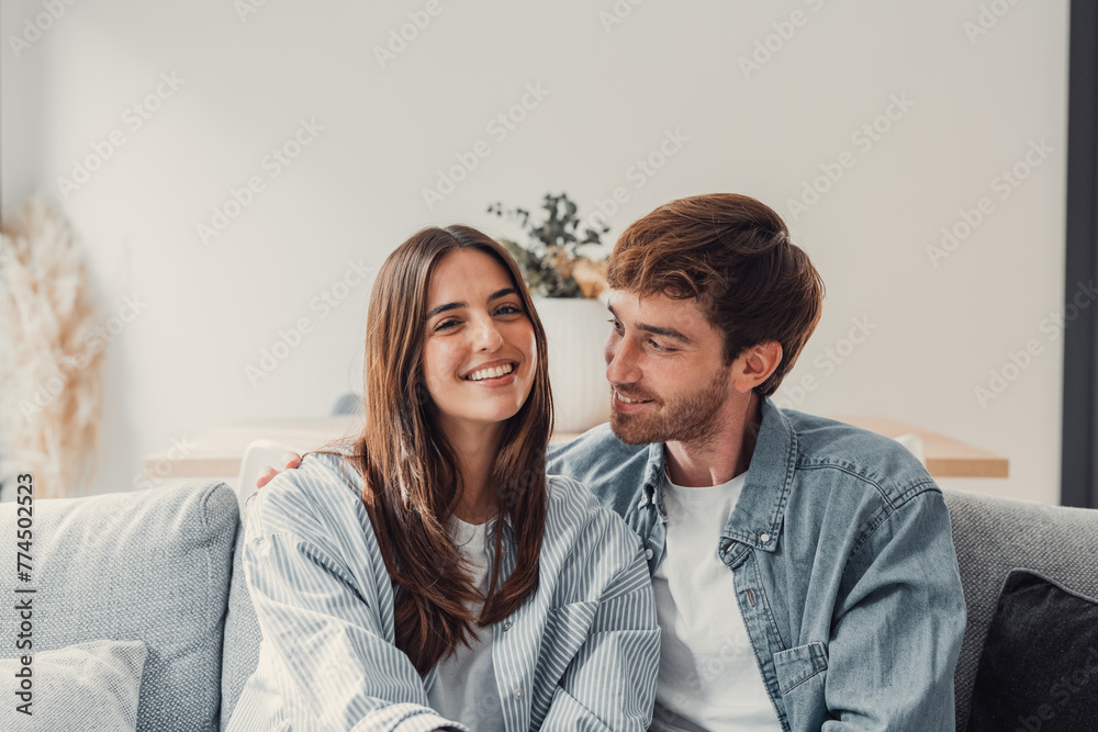 Portrait of young 20s just married couple in love posing photo shooting seated on couch in modern studio apartments, concept of capture happy moment, harmonic relationships, care and sincere feelings. Portrait of young 20s just married couple in love posing photo shooting seated on couch in modern studio apartments, concept of capture happy moment, harmonic relationships, care and sincere feelings.