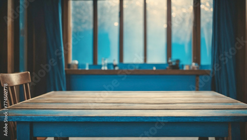 A wooden table next to a wooden chair with an unfocused window in the background. Blue theme. Concept of nostalgia.