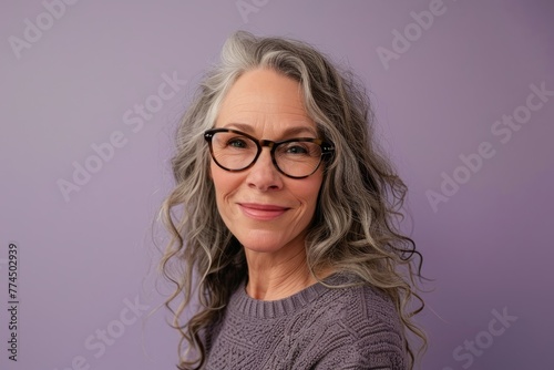 Portrait of a beautiful senior woman with glasses on purple background.