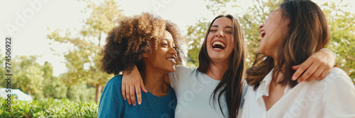 Happy multiethnic young womens talking while sitting on park bench on summer day outdoors, Panorama. Group of girls talking and laughing merrily in city park photo