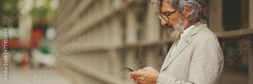 Profile mature businessman with beard in eyeglasses wearing gray jacket looking up at street signs and map trying to find her way using cellphone, Panorama