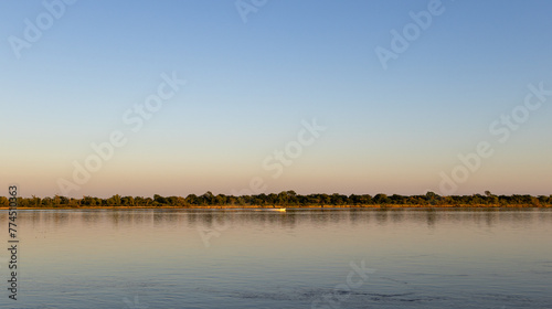 Panoramic photo of the sunrise on the Parana river. The islands and their vegetation are reflected in the calm water. © Vero Dibe