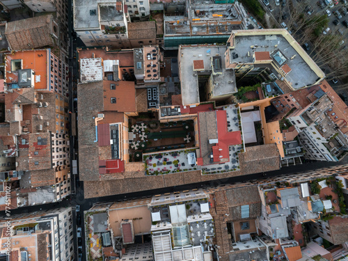 Aerial shot of Rome's dense urban zone, mixing residential and commercial structures with terracotta to grey roofs, terraces, and green spots. Its maze like design includes tight streets and alleys.